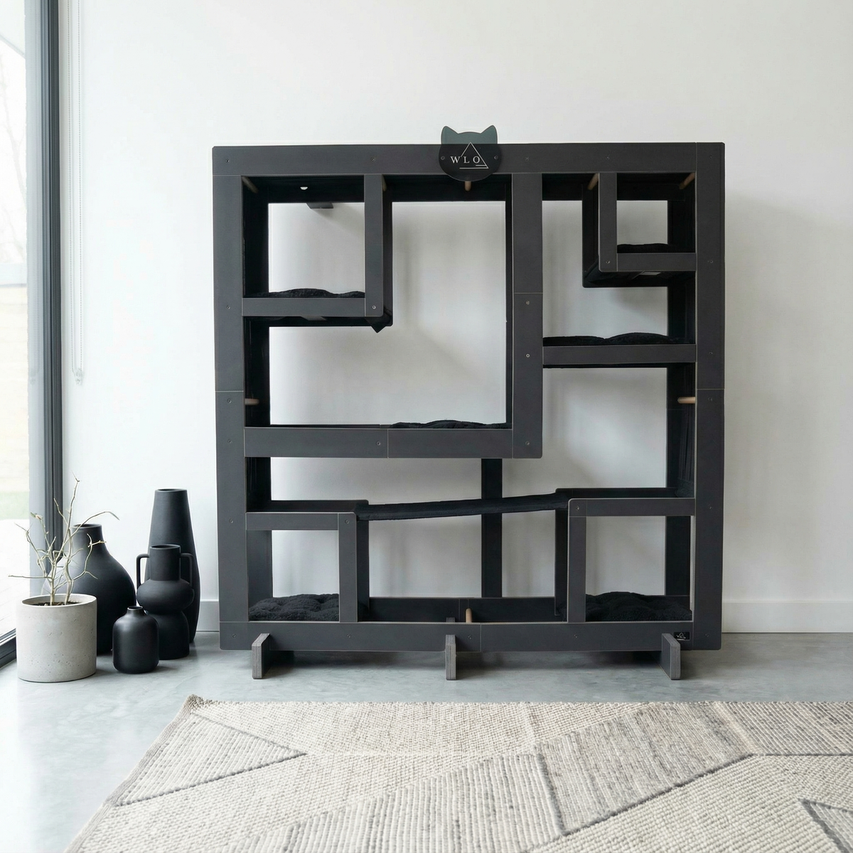 Black geometric shelf with cat sitting on top in a minimalistic room.