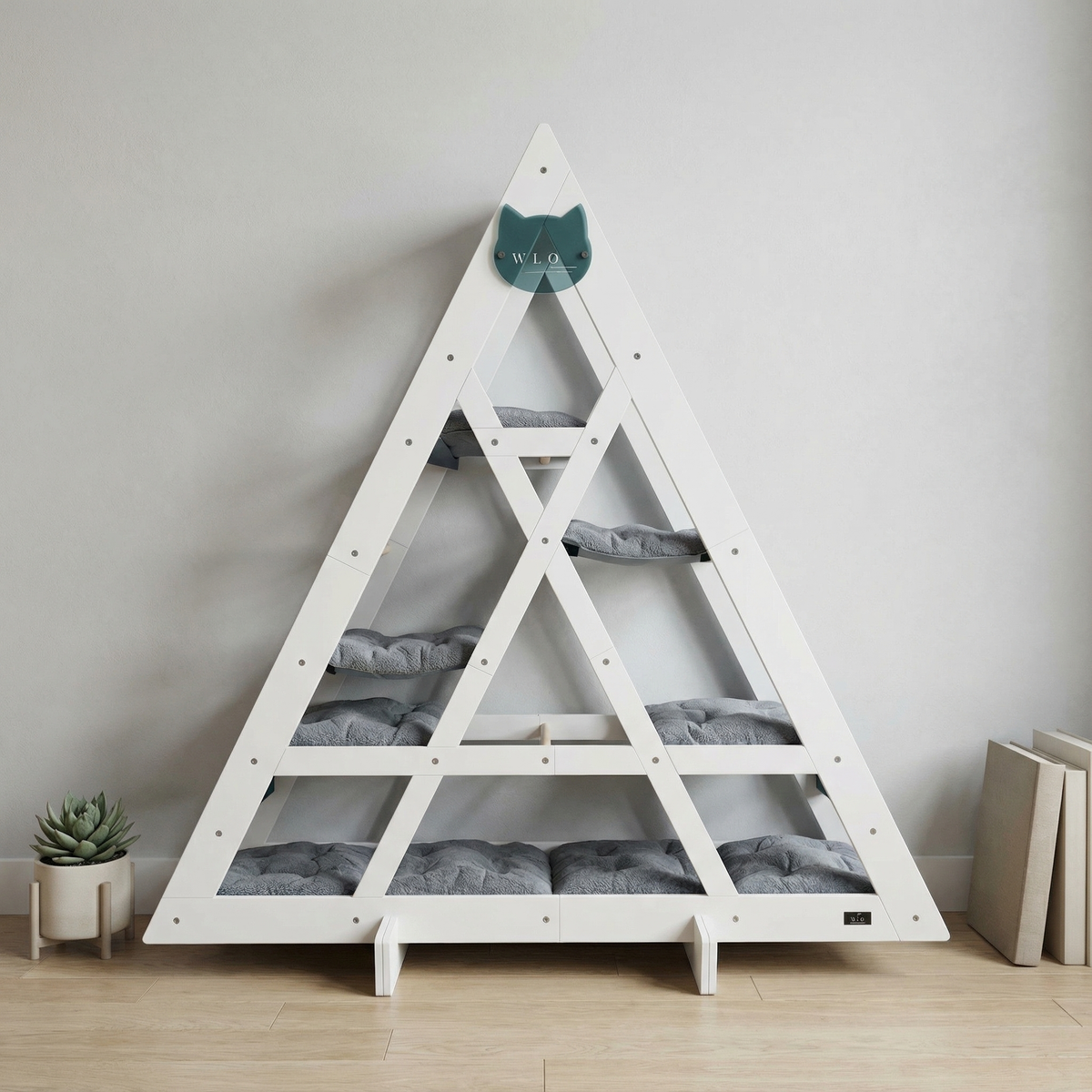White triangular pet bed with gray cushions on a wooden floor against a light gray wall.