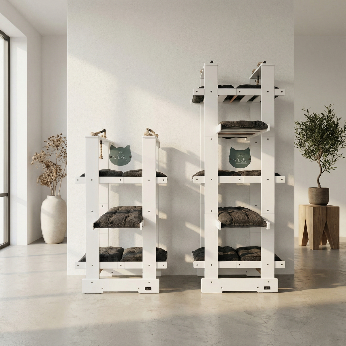 Two white cat trees with multiple levels and cushions in a minimalistic room.